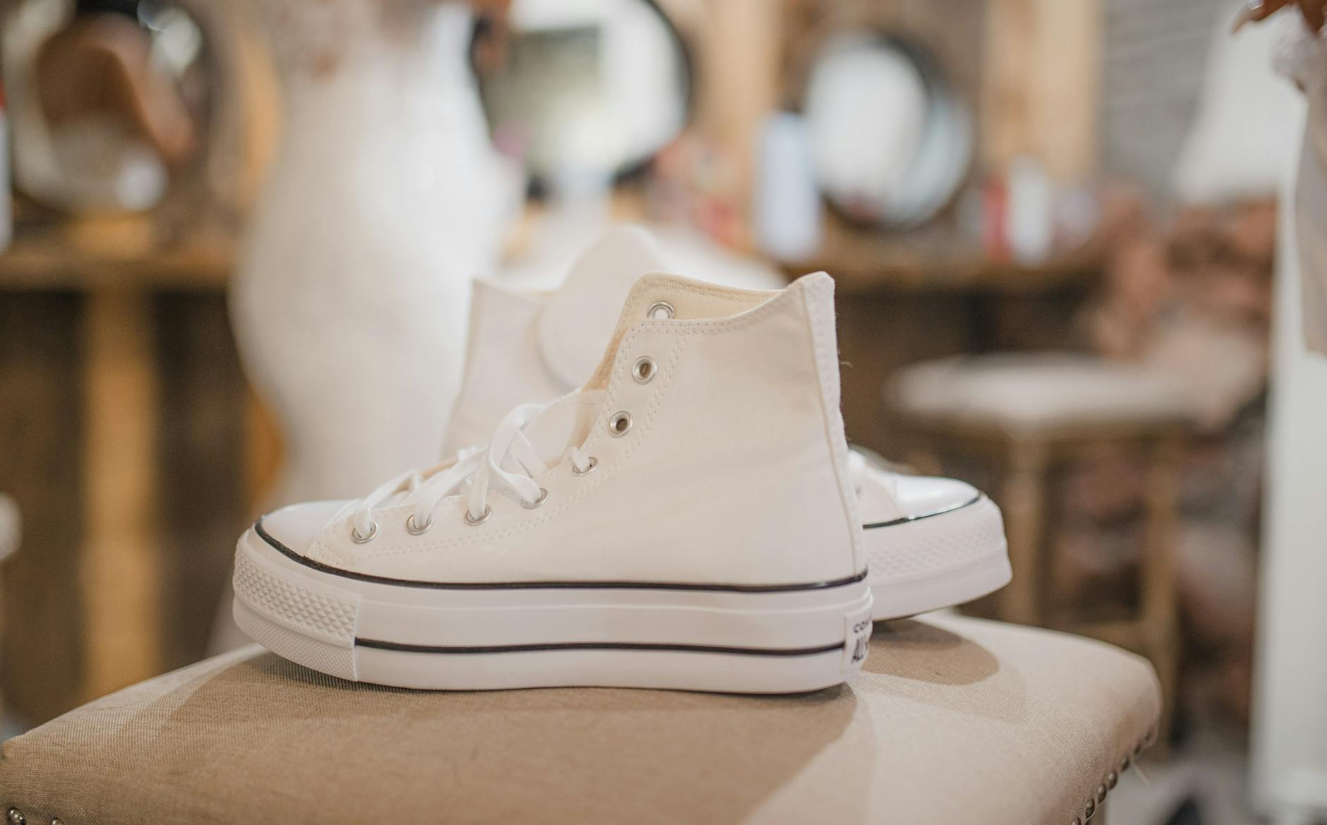 Białe trampki obok rozmazanej sukni ślubnej na tle wnętrza