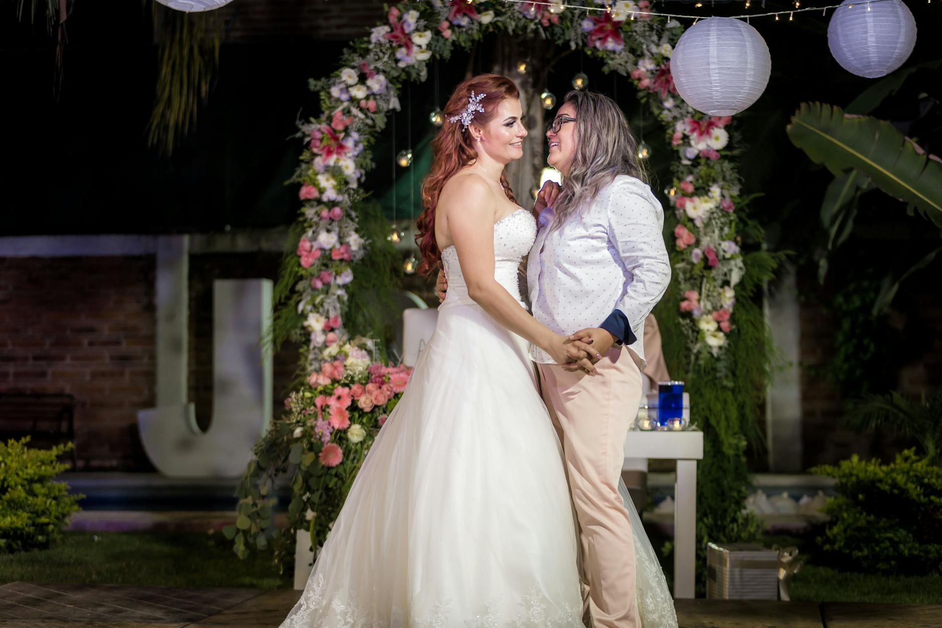 Para jednopłciowa składa przysięgę pod kwiatowym łukiem nocą