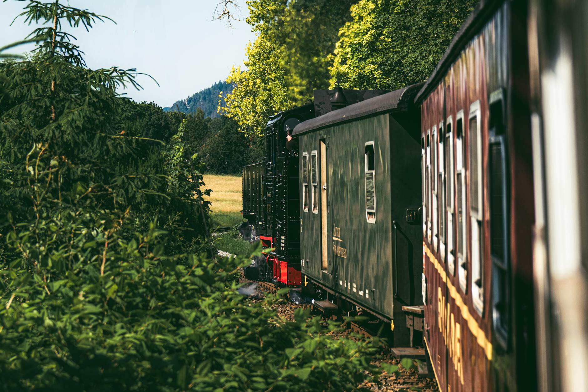 Zabytkowy pociąg parowy jedzie przez malowniczą wieś koło Zittau